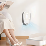 Automatic pet odor eliminator on wall near litter box and person reading, clean home setting